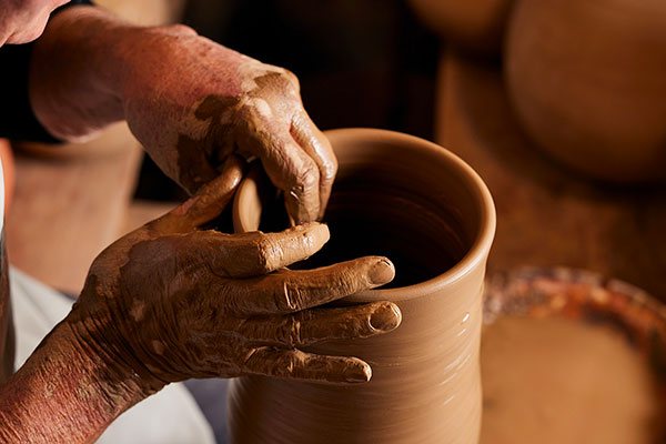 Hands shaping clay on the wheel